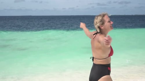 Mujer feliz divirtiéndose y bailando en la playa del mar en una isla tropical Cámara lenta