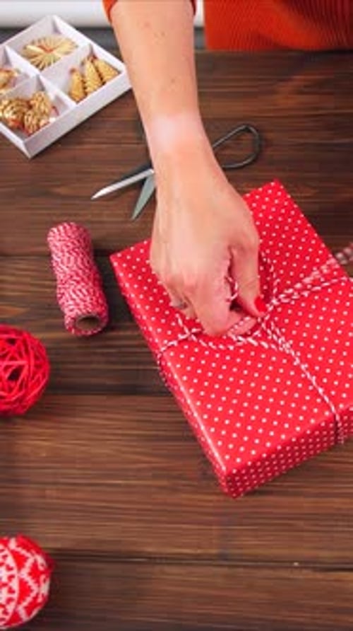 Woman Tying Red and White Ribbon on Gift