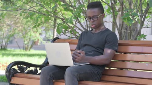 Young Adult Working on Laptop Outdoors on Bench