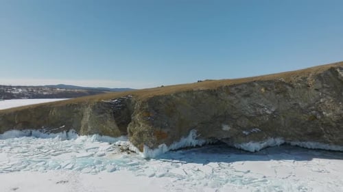 Winter aerial view of Kharantsy Island cliffs and frozen Lake Baikal ice