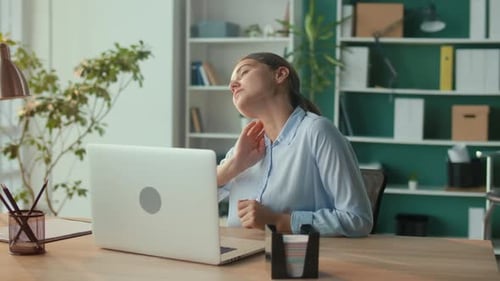 Woman Massages Stiff Neck at Office Desk