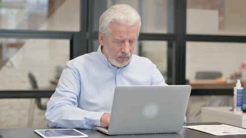 Coughing Old Businessman Using Laptop in Office