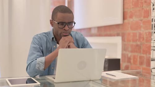 Man in Glasses Thinking at Laptop