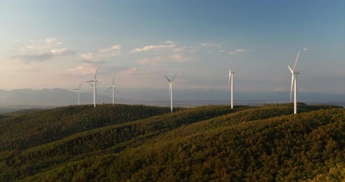 Aerial shot of wind mills rotating by the force of the wind and generating renewable energy in a g