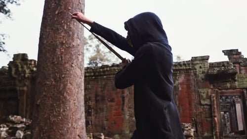 Side View Of Cloaked Man With Sword Walking