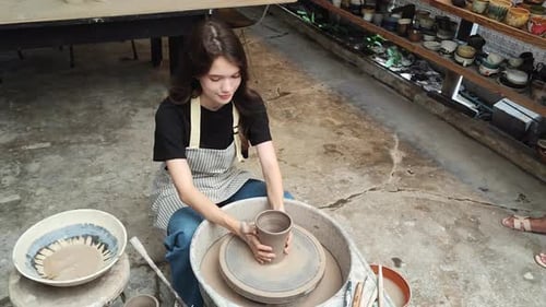 Young Woman Shaping Pottery on a Wheel in Studio