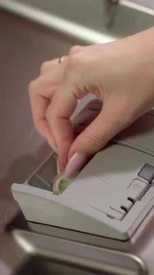 Femme plaçant une tablette pour lave-vaisselle dans le distributeur
