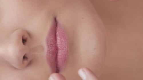 Studioporträt einer jungen, schönen und natürlichen blonden Frau, die Hautpflegecreme aufträgt, vertikales Video