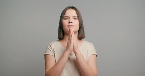 Happy Latin Teenager Girl with Fingers Crossed on Grey Background Studio and Wishing for Good Luck