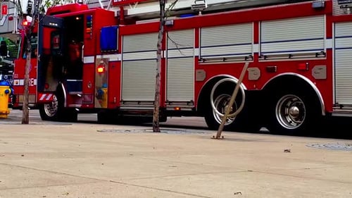 2-2Red Fire Truck parked in a downtown city next to fire hydrant and firefighter at the back door of