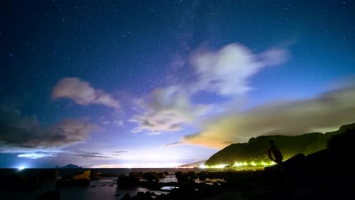 Fishing boat lights on the seaside, Milky Way and dynamic clouds in the sky.