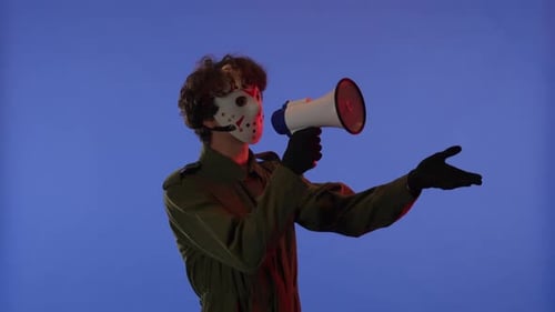 Man in White Mask with Loudspeaker in Hands on Blue Background with Red Neon Light Image of Maniac