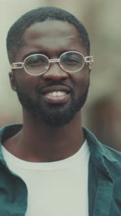 Homme souriant en tenue décontractée Image extérieure vibrante d'un homme joyeux portant des lunettes rétro