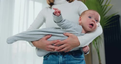 Mother Holds Cute Baby in Her Arms Indoors