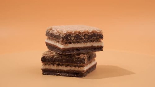 Delicious chocolate wafers with hazelnuts rotate on an orange background.
