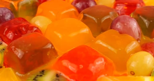 Falling drops of orange juice on a multi-colored berry gelatin jelly with grapes, orange slices