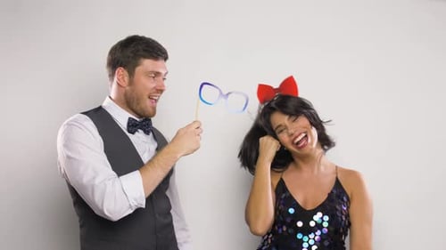 Playful couple posing with party props in studio
