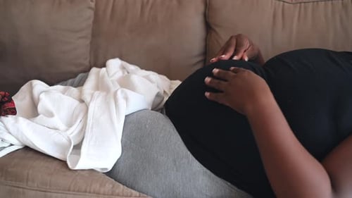 Woman Resting Hands on her Pregnant Belly on Couch