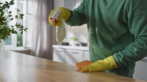 Young Adult Cleaning Kitchen Counter With Spray