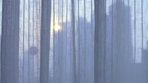 building and city line through curtains sun flairs sunshine