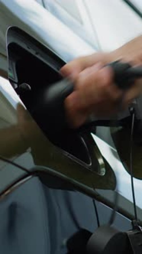 Vertical Video Close Up of Driver Disconnecting EV Vehicle From Charging Dock Low Angle Shot