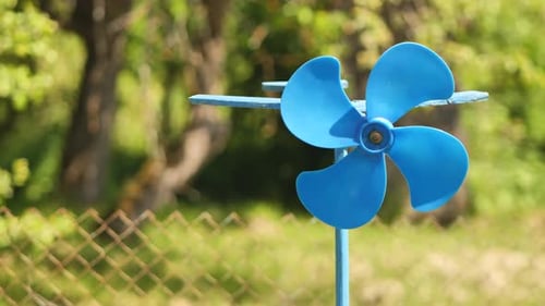 Eine blaue Fahnen-Wetterfahne dreht sich im Sommer im Wind