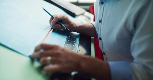 Man Drafting Blueprints with Pencil and Ruler Indoors