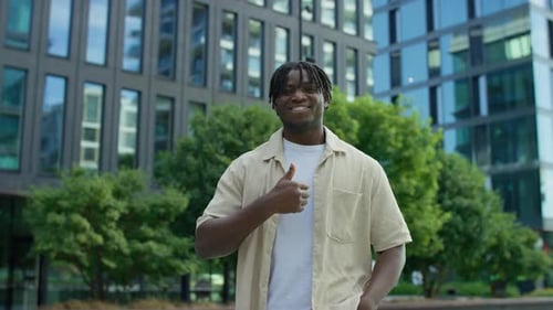 Smiling Man Giving Thumbs Up in City Setting