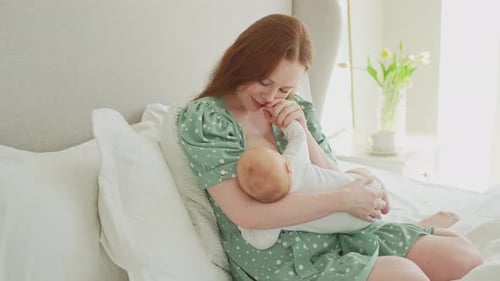 Mother Nursing Her Baby in Bed at Home