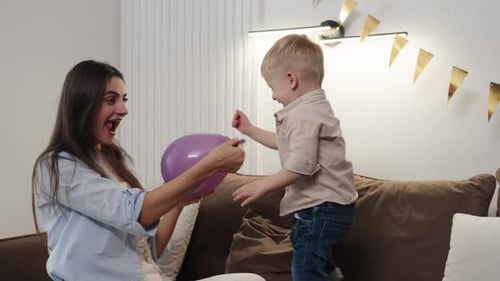 Mother and Child Playing with Balloon at Home