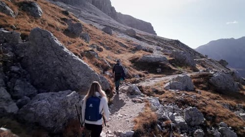 Two people hiking along mountain path on a sunny day