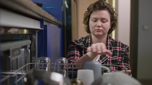 Female Hands Remove Clean Dishes From the Dishwasher in the Kitchen
