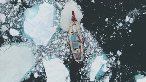 Sailing Yacht Makes Its Way Through Ice and Iceberg in Antarctica Coast Closeup View