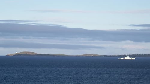 A Coastguard fisheries patrol boat drives through rough seas. The headland of the Point peninsula an