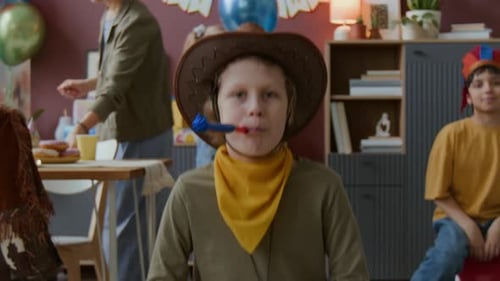Boy in Cowboy Hat Blowing Party Horn During Children Birthday Party