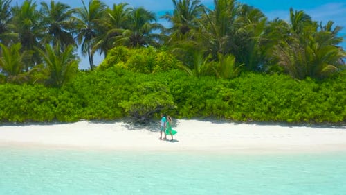Happy Couple Walks Down a Tropical Beach with Turquoise Sea in the Maldives Islands
