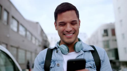 Young Adult Smiling at Mobile Phone in City