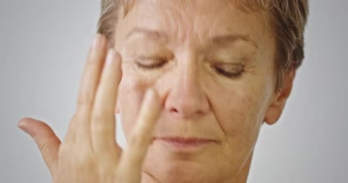 Woman Applies Lotion to Her Face in Close-Up