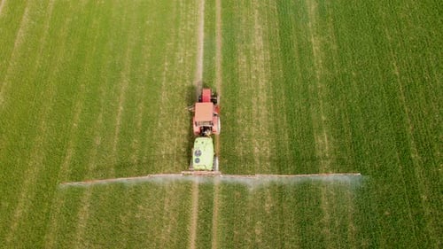 Farming Tractor Spraying on Agricultural Field with Sprayer Herbicides and Pesticides