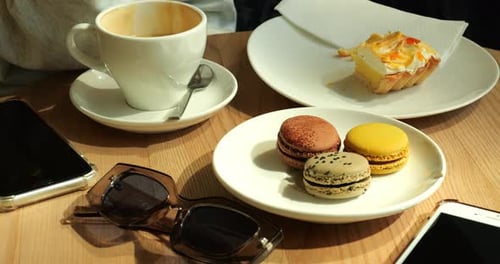 Woman Sips Coffee Savoring Assortment of Macarons and Luscious Slice of Pastry
