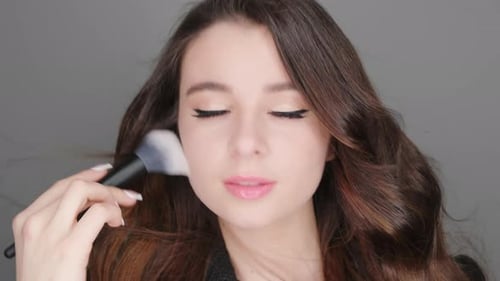 Woman Applies Makeup with a Brush