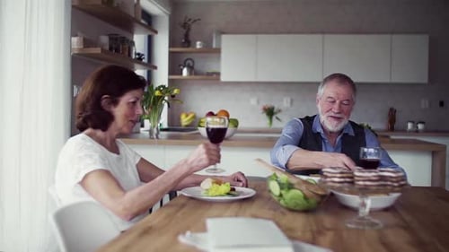 Senior Couple Toasting with Red Wine in Kitchen