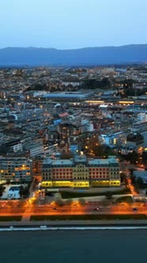 Aerial, drone view of the streets and buildings of Geneva, Switzerland in the evening. Vertical