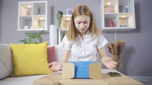 Woman Opening Box and Looking Worried at Phone