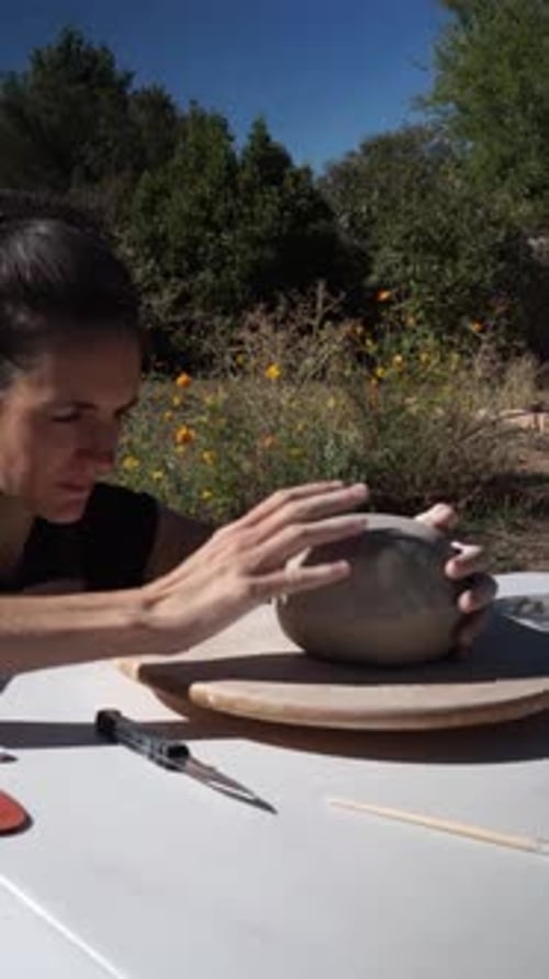 Woman Shaping Clay on Rotating Platform Outdoors