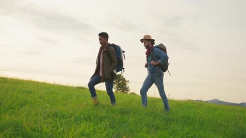 Couple Hiking Up Green Grassy Hill