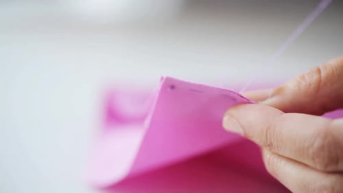 Hands Sewing Pink Fabric With Needle and Thread
