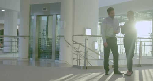 Two Business People Meeting and Looking at Digital tablet in Office Lobby