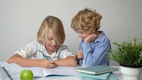Ensino Fundamental Primário, Meninos e Meninas, Irmãos, Estudando na Mesa Escrevendo em Livro e Tablet