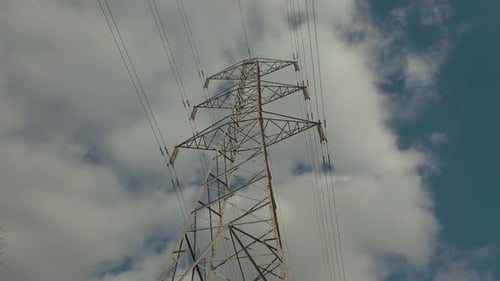 Strommast inmitten eines Bauernfeldes mit Kabeln, die sich über den blauen Himmel des